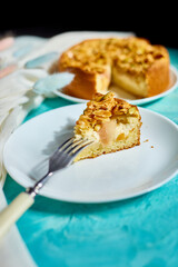 Piece of apple or pear pie, tart with caramel nuts on blue table with sunlight