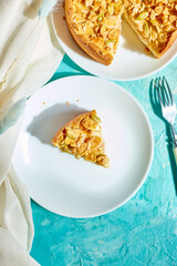 Piece of apple or pear pie, tart with caramel nuts on blue table with sunlight