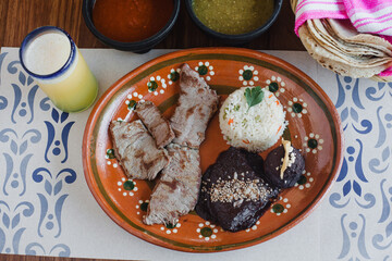 Roast beef with rice, mole poblano and refried beans, green and red sauce, tortillas and drink traditional Mexican food in Mexico