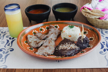 Roast beef with rice, mole poblano and refried beans, green and red sauce, drink traditional Mexican food in Mexico