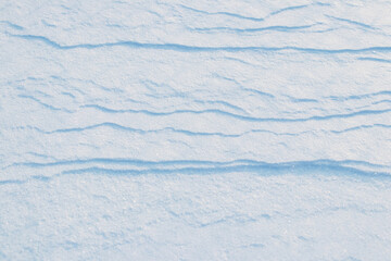 Snowy background, snow-covered surface of the earth after a blizzard in the morning in the sunlight with distinct layers of snow