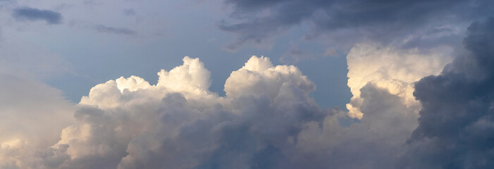 Illuminated by the evening sun, white curly clouds in a dark dramatic sky