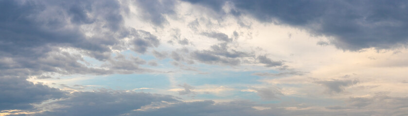 Dramatic sky with dark small clouds at sunset, panorama