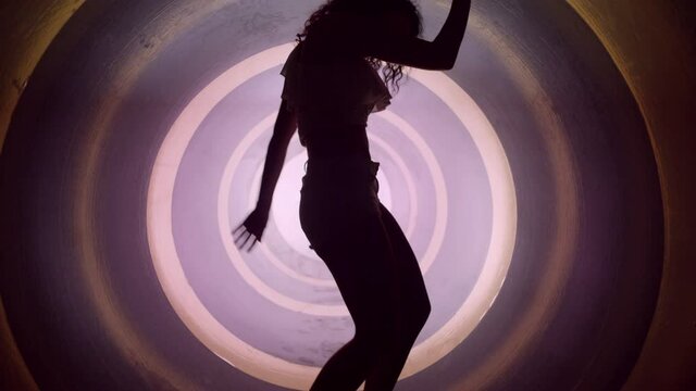 A silhouette of beautiful sexy girl , woman dancing inside circle tube . Against colored & gray background . Real decoration . None computer graphics . Shot on Arri Alexa Cinema Camera in 4K .
