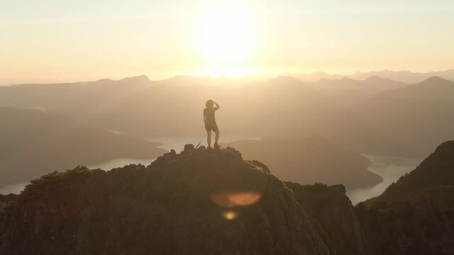Adventurous Caucasian Woman Hiking on top of a Rocky Mountain Cliff. Sunny Summer Sunset. Mnt Brunswick Hike, North of Vancouver, British Columbia, Canada.
