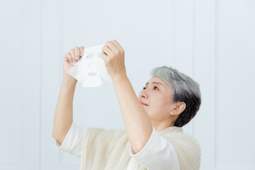 Senior Asia woman is doing the skin care with facial mask.