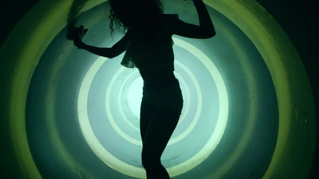 A silhouette of beautiful sexy girl , woman dancing inside circle tube . Against colored & gray background . Real decoration . None computer graphics . Shot on Arri Alexa Cinema Camera in 4K .