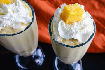 Mango Coconut Milkshakes Served in Fountain Glasses: Blended frozen drinks made with mango and coconut milk and topped with whipped cream