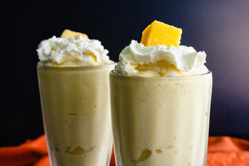Mango Coconut Milkshakes Served in Fountain Glasses: Blended frozen drinks made with mango and coconut milk and topped with whipped cream