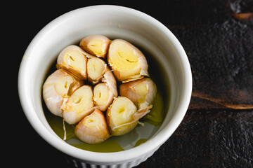 Trimmed Head of Garlic Drizzled in Olive Oil: A head of garlic in a small dish drizzled with extra virgin olive oil