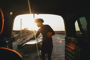young surfer with hair afro catching a surfboard in caravan