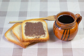 Pan tostado con café en taza de barro