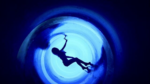 A silhouette of beautiful sexy girl , woman dancing inside circle tube . Against colored & gray background . Real decoration . None computer graphics . Shot on Arri Alexa Cinema Camera in 4K .
