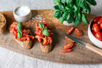 Classic bruschetta with tomatoes on a wooden cutting board.