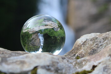 Glaskugel mit Reflektion von einem Wasserfall im Hintergrund 