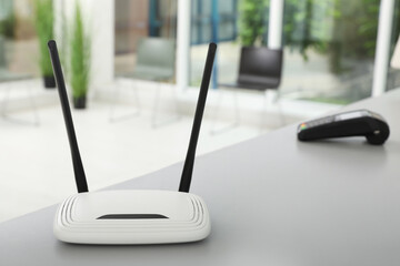 Modern Wi-Fi router on grey table indoors, space for text