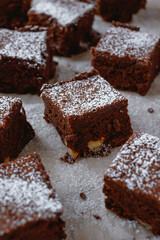 Brownie squares dusted with powdered sugar on a piece of baking parchment.  Light background.