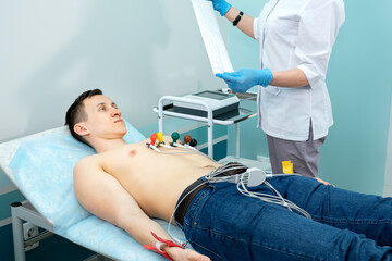 medical professional takes an electrocardiogram to a young man.