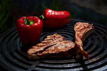 Tomahawk rib beef steak and T-bone on hot black grill.