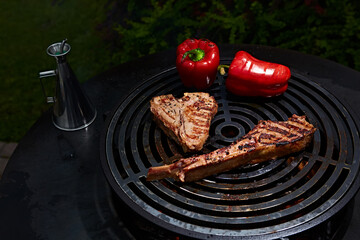 Tomahawk rib beef steak and T-bone on hot black grill.