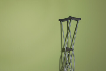 Pair of axillary crutches on light green background. Space for text