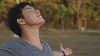 Young asian man feeling relief and relax standing outside without face mask, arms reaching out feel surrounding wind breeze, feeling the nature on travel destination, summer festival outdoor picnic