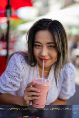 Young Petite Asian Woman Drinking a Strawberry and Banana Smoothie