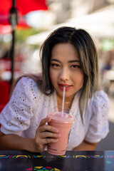 Young Petite Asian Woman Drinking a Strawberry and Banana Smoothie