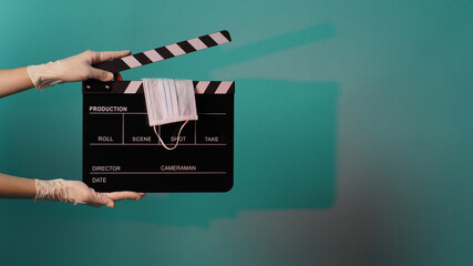 Face mask on Clapper board or movie Clapperboard and hand wear white medical gloves. it use in...