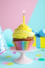 Delicious birthday cupcake with candle on color background