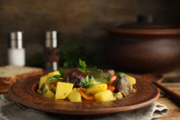 Fototapeta na wymiar Tasty cooked dish with potatoes in earthenware on wooden table