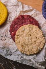 Oat and red velvet cookies on a piece of baking parchment and small cutting board. Wooden background. Scattered lavender.  Flatlay. 