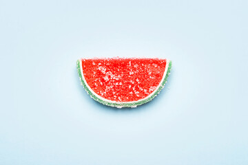 Jelly candy. One watermelon jelly candy sprinkled with sugar on a blue background. Watermelon...