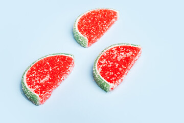 Jelly candies. Close-up of three watermelon jelly candies sprinkled with sugar on a blue background. Watermelon marmalade. Selective soft focus.