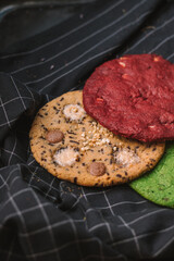 Various large colored cookies on black lined kitchen towel