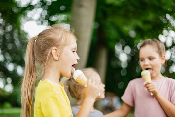 Three cheerful girls enjoy lickcing ice cream in waffle cones.