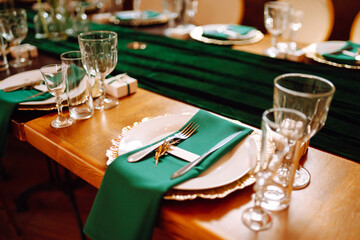 Banquet Seating Table in the restaurant in emerald color, the preparation before the banquet. The work of professional florists. Wedding, birthday, party, event concept.