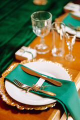 Banquet Seating Table in the restaurant in emerald color, the preparation before the banquet. The work of professional florists. Wedding, birthday, party, event concept.