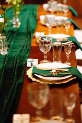 Banquet Seating Table in the restaurant in emerald color, the preparation before the banquet. The work of professional florists. Wedding, birthday, party, event concept.