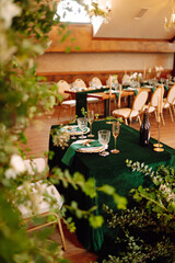 Banquet Seating Table in the restaurant in emerald color, the preparation before the banquet. The work of professional florists. Wedding, birthday, party, event concept.