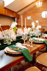 Banquet Seating Table in the restaurant in emerald color, the preparation before the banquet. The work of professional florists. Wedding, birthday, party, event concept.