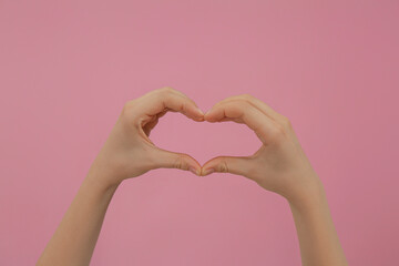 Fototapeta premium Woman making heart with fingers on pink background, closeup