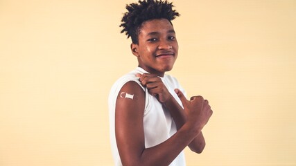 African American teenager showing COVID-19 vaccine bandage merrily in concept of coronavirus vaccination program to vaccinate citizen . - obrazy, fototapety, plakaty
