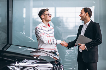 Salesman at a car showroom selling a car