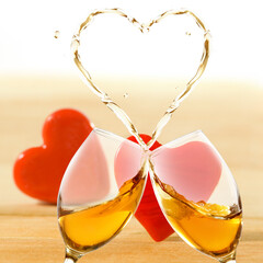 The image of two glasses from which wine is poured, in the shape of a heart.