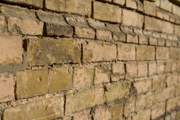 Rows of yellow faded bricks in an old brick wall. Angle perspective view to brick wall. Old brick wall.