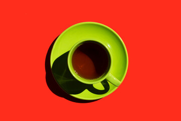 green cup and saucer with black tea or coffee on the red background. copy space. top view