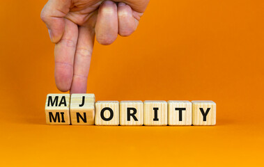 Minority or majority symbol. Businessman turns wooden cubes and changes the word 'minority' to 'majority'. Beautiful orange background. Minority or majority and business concept. Copy space.