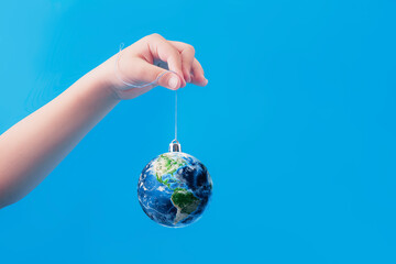 A Christmas tree toy in the shape of planet earth on a blue background