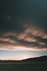Schöne Wolken nach Regen mit Feld bei Sonnenuntergang